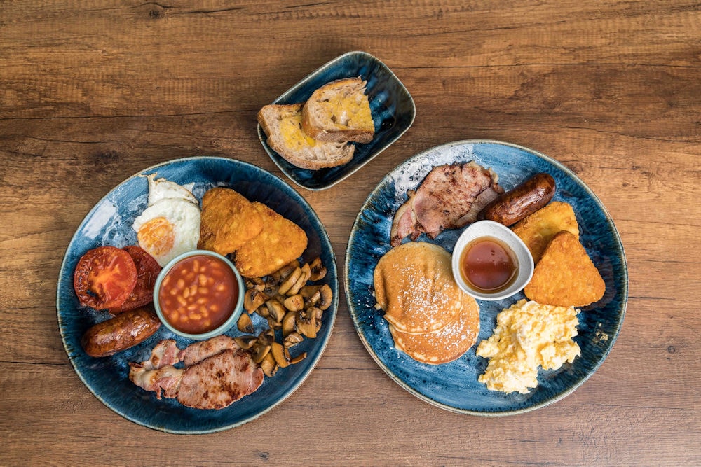 Full English and American breakfast plates on blue ceramic