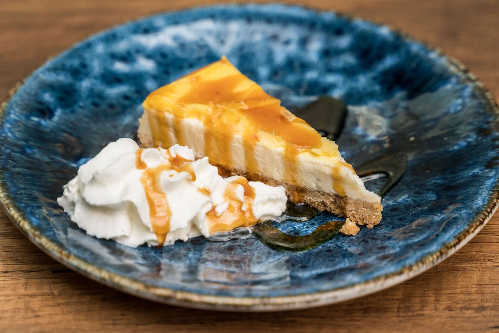 Caramel cheesecake with whipped cream on a blue plate